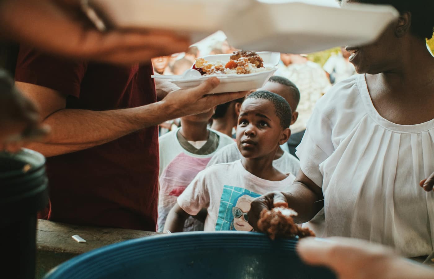 A volunteer handing a plate of food to a child